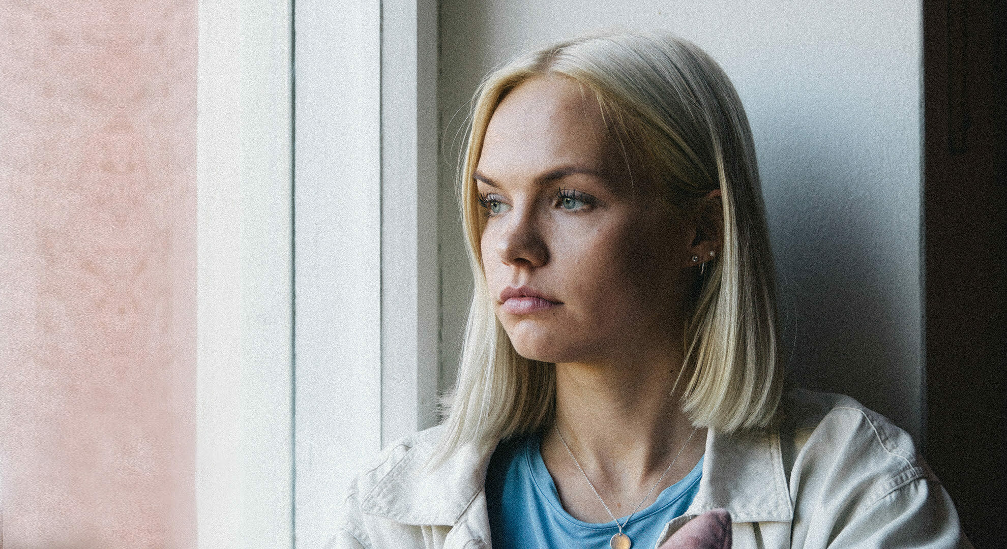 HelsinkiMission etusivun pääkuvassa nuori nainen katselee ikkunasta ulos.
