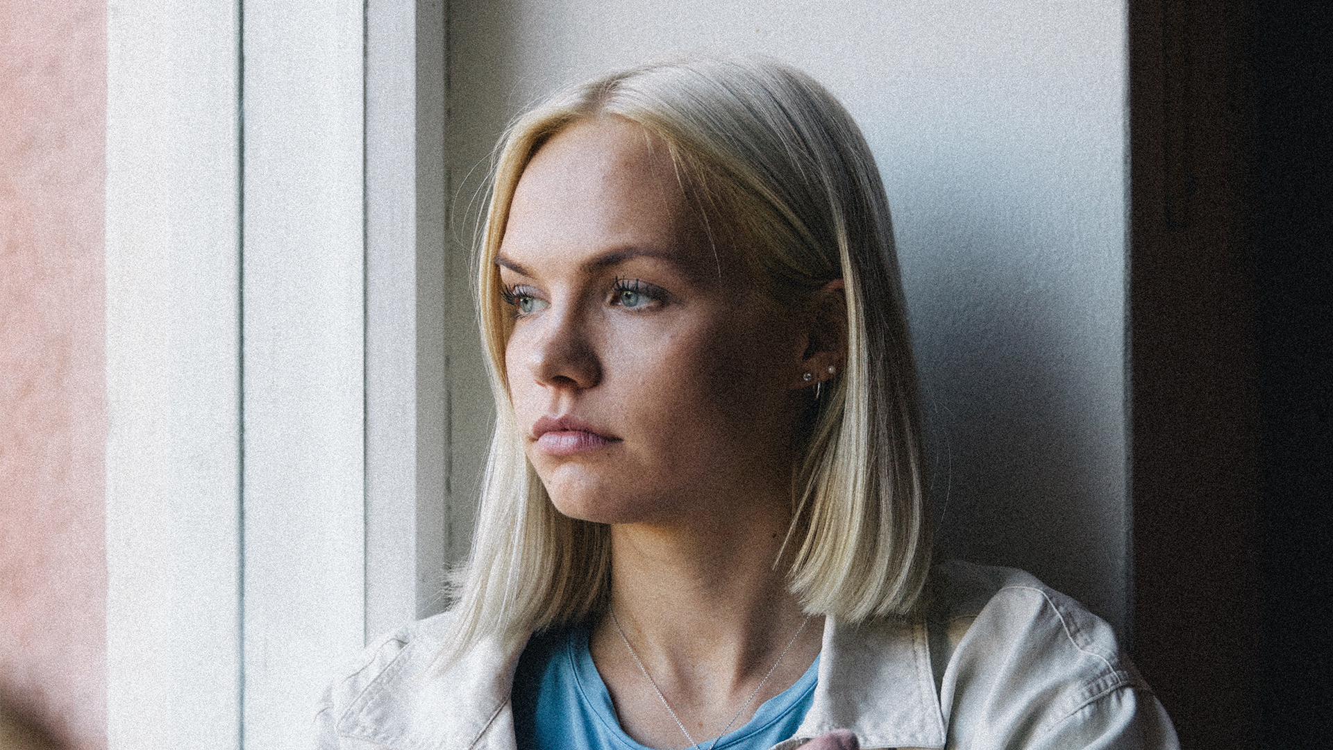 Henkilö katsoo alakuloisena ulos ikkunasta