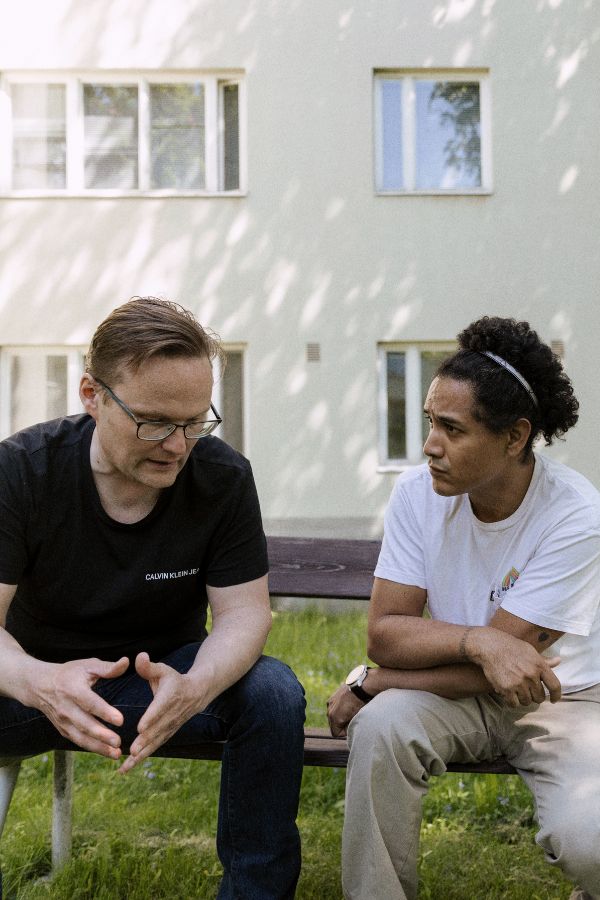 Mies keskustelee HelsinkiMission työntekijän kanssa kerrostalon pihalla.